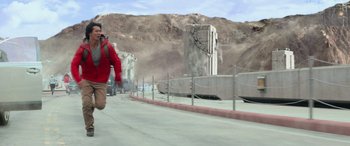 Movie still from “San Andreas” (2015), directed by Brad Peyton – A man in a red jacket walking across a bridge; Wide shot, Low angle