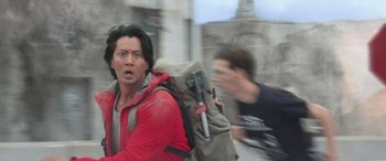 Movie still from “San Andreas” (2015), directed by Brad Peyton – A man in a red jacket is holding a backpack; Medium shot, Low angle