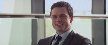 Movie still from “San Andreas” (2015), directed by Brad Peyton – A person wearing a suit and tie; Close Up shot, Over the shoulder angle