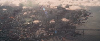 Movie still from “San Andreas” (2015), directed by Brad Peyton – An aerial view of a city with smoke billowing out of it; Extreme Wide shot, Overhead angle