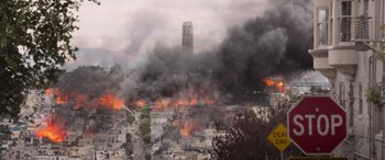 Movie still from “San Andreas” (2015), directed by Brad Peyton – A large fire burning in a city with smoke billowing out of it; Extreme Wide shot, High angle