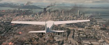 Movie still from “San Andreas” (2015), directed by Brad Peyton – An airplane flying over a city with smoke billowing out of it; Extreme Wide shot, High angle