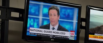 Movie still from “San Andreas” (2015), directed by Brad Peyton – A television screen with a news anchor on it; Close Up shot, Over the shoulder angle