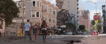 Movie still from “San Andreas” (2015), directed by Brad Peyton – Two women are walking down the street in front of some buildings; Wide shot, Over the shoulder angle