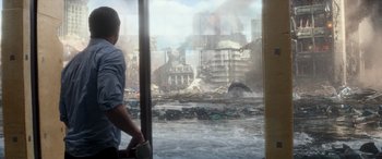 Movie still from “San Andreas” (2015), directed by Brad Peyton – A man standing in front of a window looking out at a city; Wide shot, Over the shoulder angle