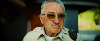 Movie still from “Savage Salvation” (2022), directed by Randall Emmett – An older man wearing sunglasses and a uniform; Close Up shot, Low angle