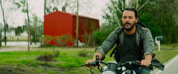 Movie still from “Savage Salvation” (2022), directed by Randall Emmett – A man riding a motorcycle in a field; Medium shot, Low angle