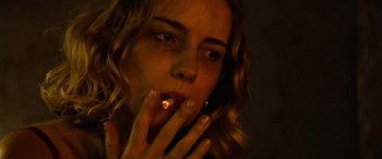 Movie still from “Savage Salvation” (2022), directed by Randall Emmett – A woman smoking a cigarette while holding a cell phone to her mouth; Close Up shot, Low angle