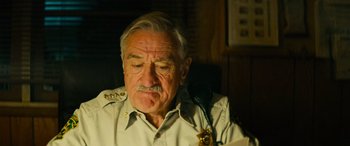 Movie still from “Savage Salvation” (2022), directed by Randall Emmett – An older man in a police uniform is on the phone; Close Up shot, Low angle