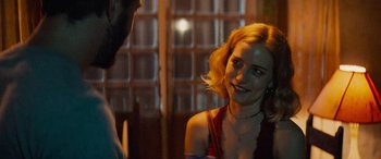 Movie still from “Savage Salvation” (2022), directed by Randall Emmett – A woman smiles at the camera while a man looks at her; Close Up shot, Over the shoulder angle