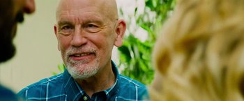 Movie still from “Savage Salvation” (2022), directed by Randall Emmett – An older man with a shaved head is smiling at the camera; Close Up shot, Over the shoulder angle
