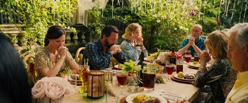 Movie still from “Savage Salvation” (2022), directed by Randall Emmett – A group of people sitting at a table with food; Medium shot, High angle