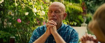 Movie still from “Savage Salvation” (2022), directed by Randall Emmett – A bald man with his hands clasped in front of his face; Close Up shot, Low angle