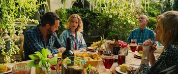Movie still from “Savage Salvation” (2022), directed by Randall Emmett – A woman sitting at a table with a bowl of corn on the cob; Medium shot, High angle