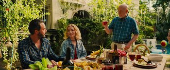 Movie still from “Savage Salvation” (2022), directed by Randall Emmett – A group of people sitting at a table with food and drinks; Medium shot, Over the shoulder angle