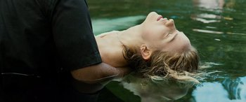 Movie still from “Savage Salvation” (2022), directed by Randall Emmett – A woman laying in the water with her eyes closed; Close Up shot, Overhead angle