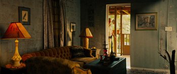 Movie still from “Savage Salvation” (2022), directed by Randall Emmett – A living room filled with furniture next to an open door; Wide shot, Low angle