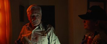 Movie still from “Savage Salvation” (2022), directed by Randall Emmett – An older man in a police uniform is looking at the camera; Close Up shot, Over the shoulder angle