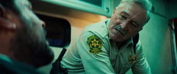 Movie still from “Savage Salvation” (2022), directed by Randall Emmett – A police officer is sitting in front of a camera; Close Up shot, Low angle