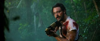 Movie still from “Savage Salvation” (2022), directed by Randall Emmett – A man holding a gun with blood all over it; Medium shot, Low angle