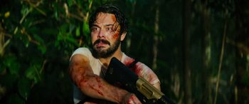 Movie still from “Savage Salvation” (2022), directed by Randall Emmett – A man holding a gun with blood all over his face; Medium shot, Low angle