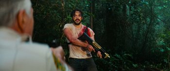 Movie still from “Savage Salvation” (2022), directed by Randall Emmett – A man holding a gun with blood all over his face; Medium shot, Over the shoulder angle