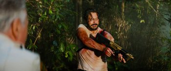 Movie still from “Savage Salvation” (2022), directed by Randall Emmett – A man in a white shirt is holding a gun; Medium shot, Low angle