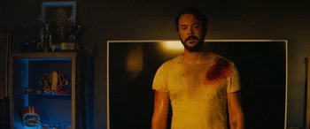 Movie still from “Savage Salvation” (2022), directed by Randall Emmett – A man in a yellow shirt with a blood wound on his chest; Medium shot, Low angle