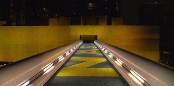 Movie still from “Savage x Fenty Show Vol. 3” (2021), directed by Alex Rudzinski – An airport baggage claim conveyor belt at an airport; Extreme Wide shot, Overhead angle