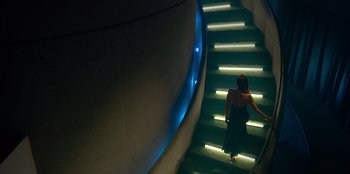 Movie still from “Savage x Fenty Show Vol. 3” (2021), directed by Alex Rudzinski – A woman in a black dress walking up a flight of stairs; Wide shot, Low angle