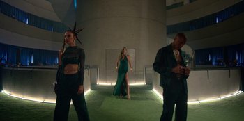 Movie still from “Savage x Fenty Show Vol. 3” (2021), directed by Alex Rudzinski – A woman in a green dress standing next to two men; Wide shot, Low angle