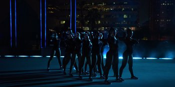 Movie still from “Savage x Fenty Show Vol. 3” (2021), directed by Alex Rudzinski – A group of women in black leotards standing in the dark; Extreme Wide shot, Low angle