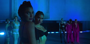 Movie still from “Savage x Fenty Show Vol. 3” (2021), directed by Alex Rudzinski – Two beautiful women posing for a picture in a dark room; Medium shot, Low angle