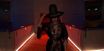 Movie still from “Savage x Fenty Show Vol. 3” (2021), directed by Alex Rudzinski – A woman wearing a black top hat in a dark room; Medium shot, Low angle