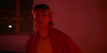 Movie still from “Savage x Fenty Show Vol. 3” (2021), directed by Alex Rudzinski – A man with long blonde hair wearing a red shirt; Close Up shot, Low angle