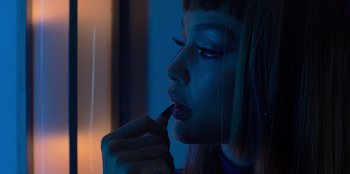 Movie still from “Savage x Fenty Show Vol. 3” (2021), directed by Alex Rudzinski – A woman with blue eyes is putting lipstick on her lips; Close Up shot, Low angle