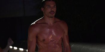 Movie still from “Savage x Fenty Show Vol. 3” (2021), directed by Alex Rudzinski – A man with no shirt standing in the dark; Medium shot, High angle