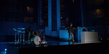 Movie still from “Savage x Fenty Show Vol. 3” (2021), directed by Alex Rudzinski – A man standing in front of a drum set on a stage; Extreme Wide shot, Low angle