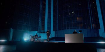 Movie still from “Savage x Fenty Show Vol. 3” (2021), directed by Alex Rudzinski – A man walking across a stage in front of a building; Extreme Wide shot, Low angle