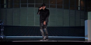 Movie still from “Savage x Fenty Show Vol. 3” (2021), directed by Alex Rudzinski – A man in a black jacket is singing on a stage; Wide shot, Low angle