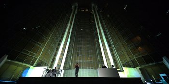 Movie still from “Savage x Fenty Show Vol. 3” (2021), directed by Alex Rudzinski – A person standing in front of a building at night; Extreme Wide shot, Low angle
