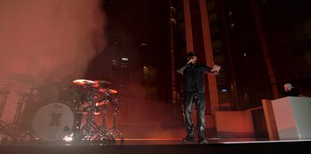 Movie still from “Savage x Fenty Show Vol. 3” (2021), directed by Alex Rudzinski – A man standing on a stage next to a drum set; Wide shot, Low angle