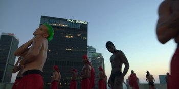Movie still from “Savage x Fenty Show Vol. 3” (2021), directed by Alex Rudzinski – A group of men in red bathing suits standing in front of a building; Extreme Wide shot, Low angle
