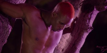 Movie still from “Savage x Fenty Show Vol. 4” (2022), directed by Alex Rudzinski – A man with a red mohawk is standing next to a tree; Medium shot, Low angle
