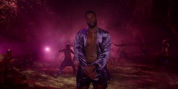 Movie still from “Savage x Fenty Show Vol. 4” (2022), directed by Alex Rudzinski – A man standing in a field with a bunch of other people; Wide shot, Low angle