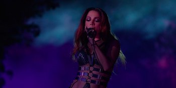 Movie still from “Savage x Fenty Show Vol. 4” (2022), directed by Alex Rudzinski – A woman in fishnet lingerie is singing into a microphone; Medium shot, Low angle