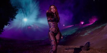 Movie still from “Savage x Fenty Show Vol. 4” (2022), directed by Alex Rudzinski – A woman in a see through body suit holding a microphone in her hand; Medium shot, Low angle
