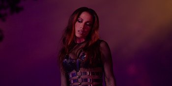 Movie still from “Savage x Fenty Show Vol. 4” (2022), directed by Alex Rudzinski – A woman in a fishnet top posing for a picture; Medium shot, Low angle