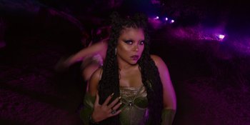 Movie still from “Savage x Fenty Show Vol. 4” (2022), directed by Alex Rudzinski – A woman with long black dreadlocks in front of purple lights; Close Up shot, Over the shoulder angle