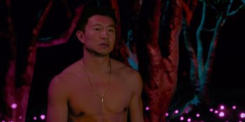 Movie still from “Savage x Fenty Show Vol. 4” (2022), directed by Alex Rudzinski – A shirtless man standing in front of some trees; Medium shot, Over the shoulder angle